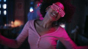 Close Up Portrait of Diverse Multiethnic Couple in Casual Clothes and Futuristic Neon Glowing Glasses, Dance and Have a Party at Home in Loft Apartment. Recording Funny Viral Videos for Social Media.