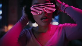 Close Up Portrait of Diverse Multiethnic Young Brazilian Female Dancing in Futuristic Neon Glowing Glasses, Having a Party at Home in Loft Apartment. Recording Funny Viral Videos for Social Media.