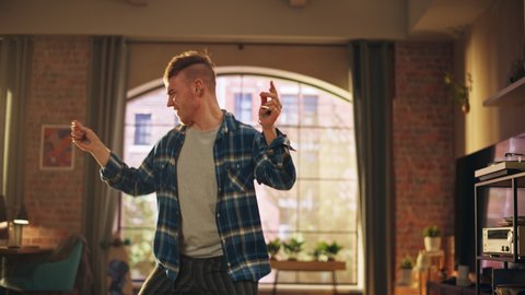 Portrait of Happy Handsome Young Man Dancing in Casual Home Clothes, Enjoying His Time Alone in His Loft Apartment. Recording Funny Viral Videos for Social Media. Medium Shot.