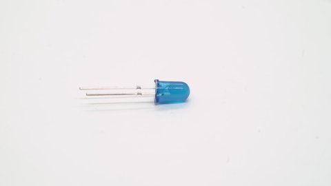 Blue LED electronic component rotates on white background isolated. Light emitting diode. DIY. Optic electric technology.