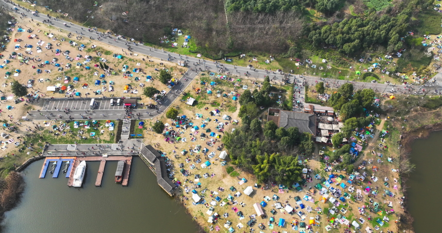 Crowds camping on the lawn in the spring park by the lake aerial top view 4k time lapse Aerial hyper lapse clip