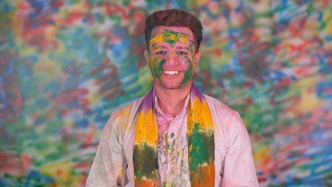 A man in white kurta blowing gulal from his hand on the eve of Holi - colorful holi, Holi color sprinkle. A Happy young Indian man blowing color and celebrating Holi.