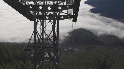 North Vancouver, British Columbia, Canada - Feb 1, 2022: Aerial View of Gondola Tower over Evergreen Trees covered during winter season day. Grouse Mountain, Slow Motion