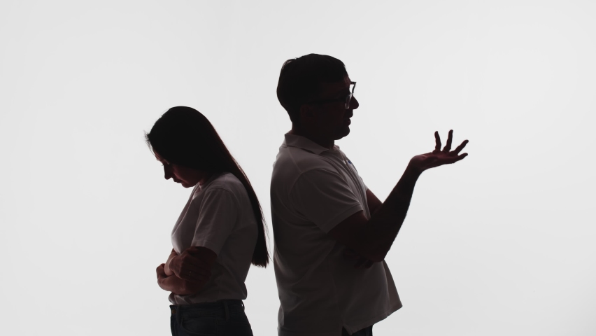 Silhouette of married couple, husband and wife standing with their backs to each other and arguing, white background in studio, side view. Concept of problems in family