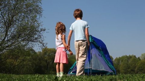 boy and little girl put up tent in woods hot summer