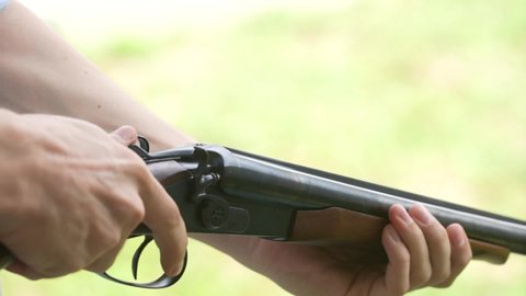 Man with his fingers takes out spent cartridges from gun barrel from the trunks of smooth-bore hunting rifle after firing. Slow motion. Hunter man reloading cartridges in in a double-barreled rifle 