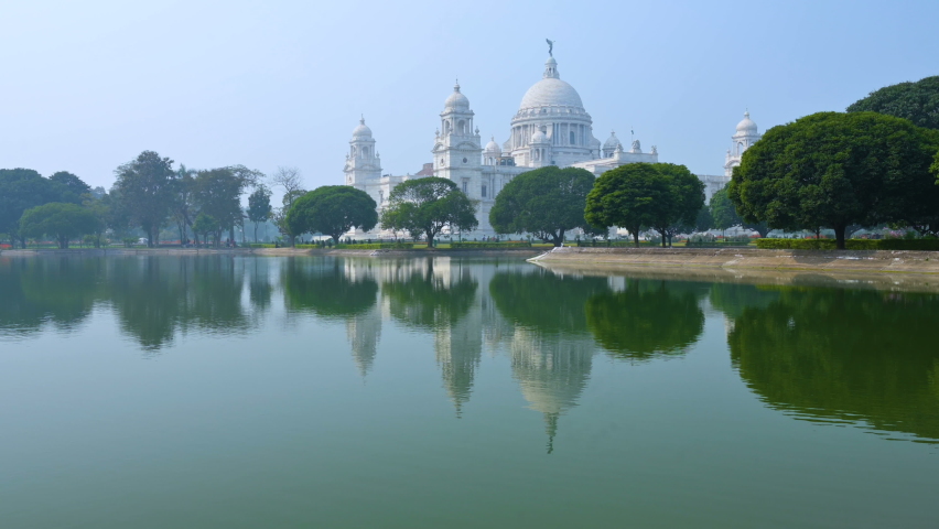 4K stock video of Victoria Memorial, a large marble building in Central Kolkata, It is one of the famous monuments of Kolkata, West Bengal, India. Reflection on the lake water in midddleground.