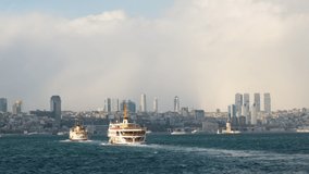 Two ferry boats are carrying passengers on The Istanbul Bosphorus on a sunny day. The urban skyline in the background is looking awesome.