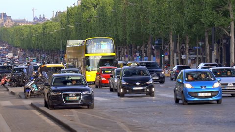 Paris, France - May 2019 : Cars and  yellow open tour bus driving on the Champs-Elysees avenue in Paris, France
