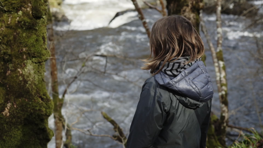 Slow motion - Boy watching rushing River in Scottish Forest
