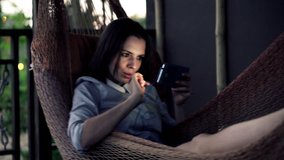 Happy, young businesswoman watching film on smartphone on hammock
