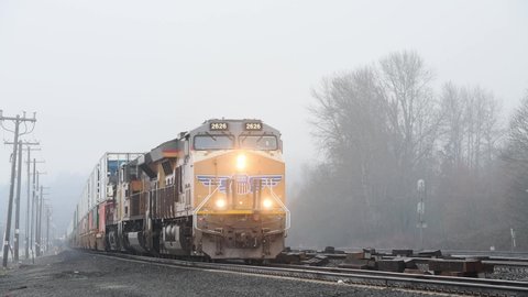 Seattle - March 06, 2022; Union Pacific intermodal freight train slowly approaches on a misty day with bright headlights