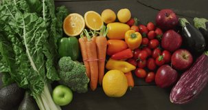 Video of fresh colourful fruit and vegetables on wooden boards in background. fresh vegan food, healthy eating concept digitally generated video.