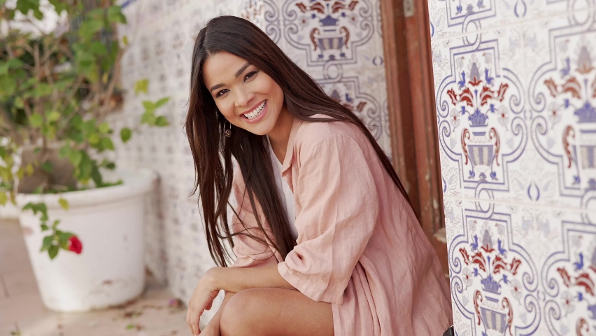 Smiling ethnic woman sitting on street
