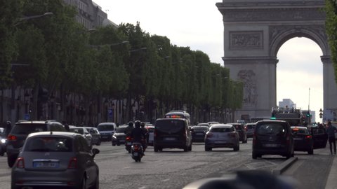 Paris, France - May 2019 : Arc de Triomphe and heavy traffic of cars driving on the Champs-Elysees avenue at the end of the day in Paris, France