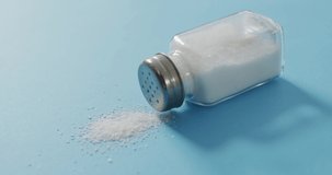 Video of salt in a salt shaker on blue background. food and cooking ingredients concept.