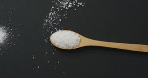 Video of salt in a salt shaker and spoon on black background. food and cooking ingredients concept.