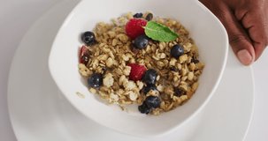 Video of cereals and fruit in ceramic bowl on white kitchen worktop. breakfast food and cooking ingredients concept.