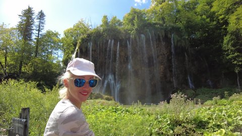 Woman looking the waterfalls of Plitvice Lakes National Park in Croatia. Natural forest park with lakes and falls in the Lika region. UNESCO World Heritage of Croatia named Plitvicka Jezera