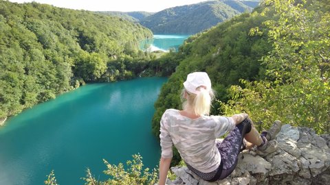 Girl sitting on viewpoint the Plitvice Lakes National Park of Croatia in Lika region. Kozjak and Milanovac lakes overlook. UNESCO World Heritage of Croatia named Plitvicka Jezera.