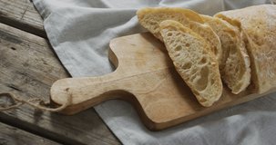 Video of bread on chopping wooden board on wooden worktop. food and cooking ingredients concept.