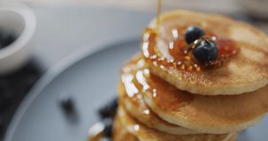 Video of pancakes on plate seen from above on wooden background. dessert, food and cooking ingredients concept.