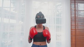 Female is punching boxing. Asian woman in vr headset boxing doing exercise in home. Fun and happy women, healthy lifestyle, health care, technology, virtual reality simulator. Slow Motion