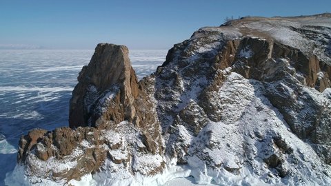 Aerial view of cape Khoboy, Olkhon island. Tall rocks in frozen lake Baikal. Popular touristic destination. Winter landscape. Panoramic view