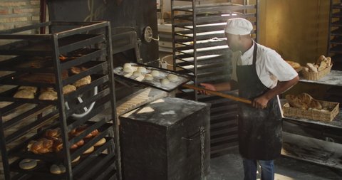 Animation of african american male baker putting rolls into furnace. working at bakery, independent small business.