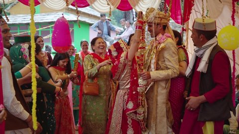 A Happy Indian bride and groom or a married couple dressed in traditional or ethnic attire are performing a ritual during a Hindu wedding ceremony in the countryside, Manali, India (March 2022)