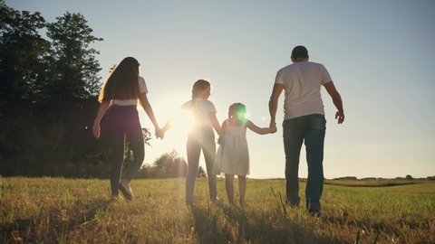 Silhouette of friendly family holding hands in sunset.happy children parents are walking park.Happy dream to be together.Silhouette at sunset parents,children holding hands.family walks through park.
