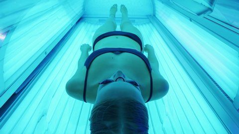 Sun treatments in a horizontal solarium, young woman takes a sun bath in a solarium, blue light.