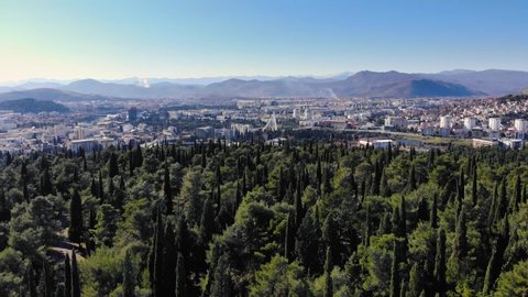 Cinematic, Panoramic Aerial View of Podgorica, Flying from behind the Gorica Park Hill with the Mountains in the background