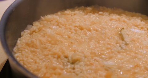 Close up view of delicious risotto in the frying pan. Hot broth in a pan. Risotto rice been cooked.