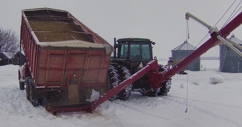 Boyle , Alberta , Canada - 02 28 2022: Unloading grain from a tandem grain truck into a swing auger on a snowy day 