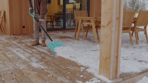 Man shovelling snow on patio switching off light with smartphone