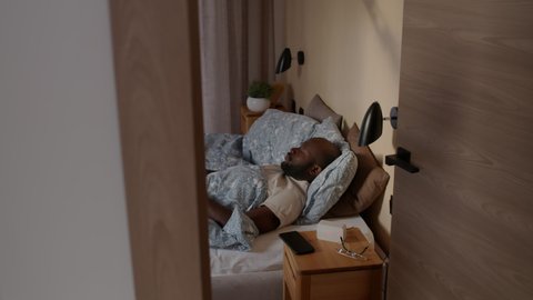 Man waking up in bed switching on light with smartphone
