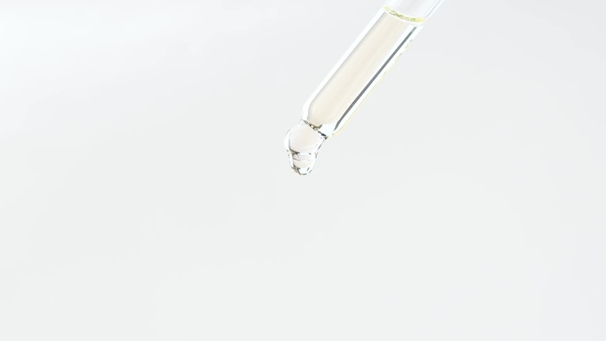 Glass dropper with cosmetic liquid on a plain background close-up. | Shutterstock HD Video #1088042753