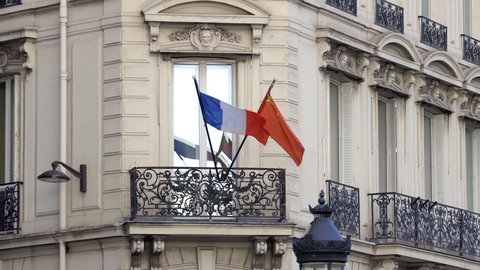 Paris, France - May 2019 : French and chinese flag waving on a balcony on the Champs-Elysees avenue in Paris, France