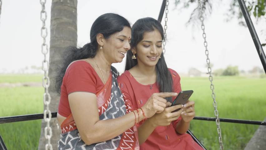 Relaxed mother and daughter on swing using mobile phone - concept of happiness, bonding, using social media and Indian family Royalty-Free Stock Footage #1088048865