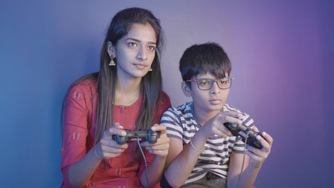 Siblings fighting each other while playing video game at home - concept of brother and sister quarrel, bonding and entertainment