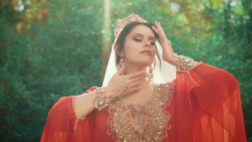 beautiful oriental woman. Red traditional dress medieval vintage clothes. Lady Queen of Ottoman Empire. Gold crown jewelry bracelets earrings accessory. Face bright makeup. Girl fashion model posing