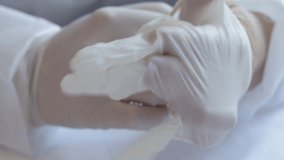close up video of a doctor or nurse in white robe is putting surgical gloves, professional medical safety and hygiene for medical exams for protection against viruses. medical concept