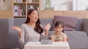 Happy asian mother and daughter sing a song and dancing together watching music video apps in smartphone.Cheerful mom and kid recording video clip and sharing on social media streaming app having fun