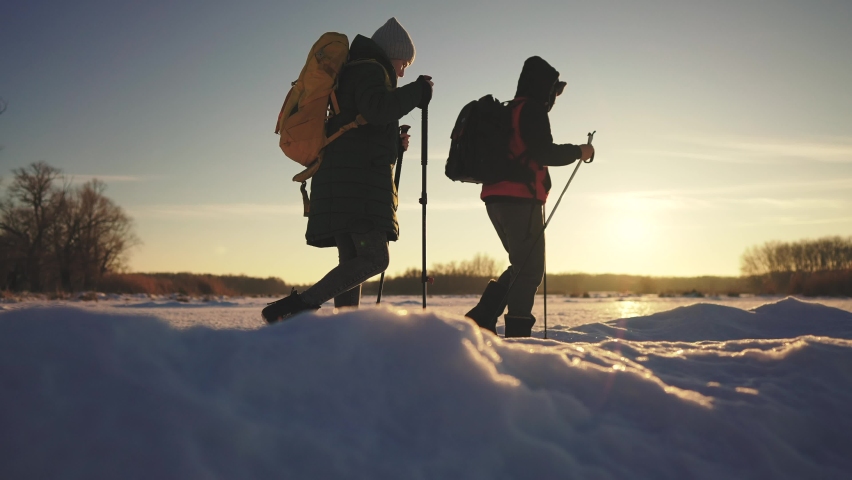 nordic walking in winter. winter hike group of tourists silhouette. teamwork travel. two hikers with sticks walk in sunset the winter in the snow at silhouette. activities in winter happy family Royalty-Free Stock Footage #1088054397