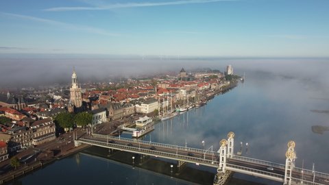 Kampen aerial drone view over the IJssel river during a foggy sunrise at the start of an autumn day with mist and blue skies.Kampen is an ancient Hanseatic League city at the shore of the river IJssel