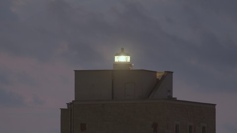 Lighthouse building silhouette on the sea. Giving a light signal to the distance for navigation. Two fast blinks.