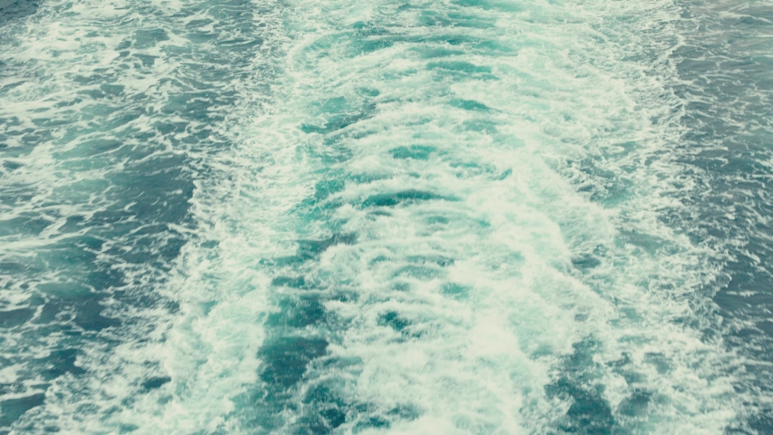 Water churning behind a large boat in the ocean