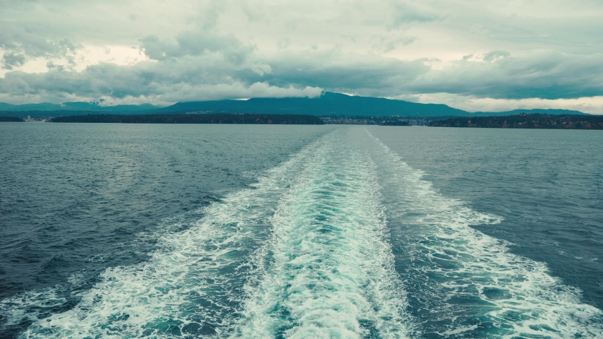 Looking off the back of a large ferry at distant coastline