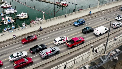 Canadian Flags On Cars With People Walking At The Burrard Bridge During Truckers Convoy Protest In Vancouver, Canada. No To Mandatory Vaccination. aerial drone descend